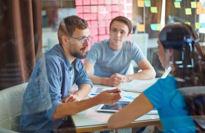 Young man consulting his business partner at meeting in office