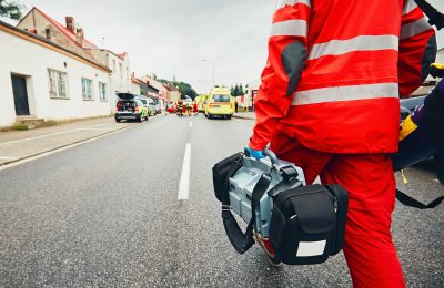 Hand of the doctor with defibrillator. Teams of the Emergency medical service are responding to an traffic accident.